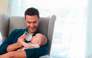 Man feeding a baby with a Chicco bottle